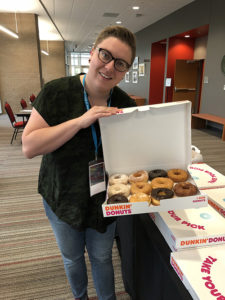 A woman holds open a box of donuts